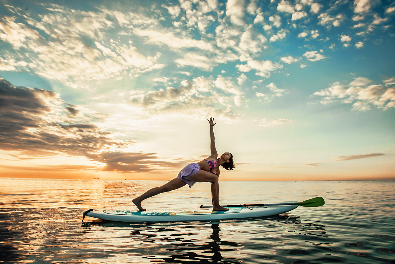 young woman doing yoga on a sup board in the lake BBVVTFX